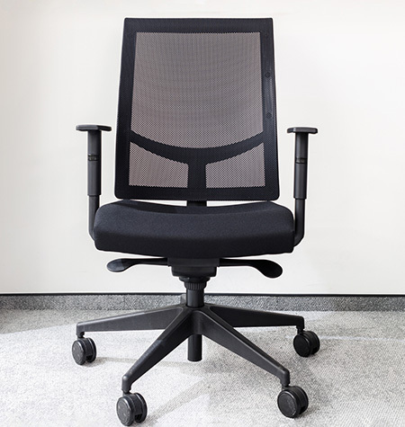 Modern ergonomic office chair in an empty office against white wall on gray carpet 